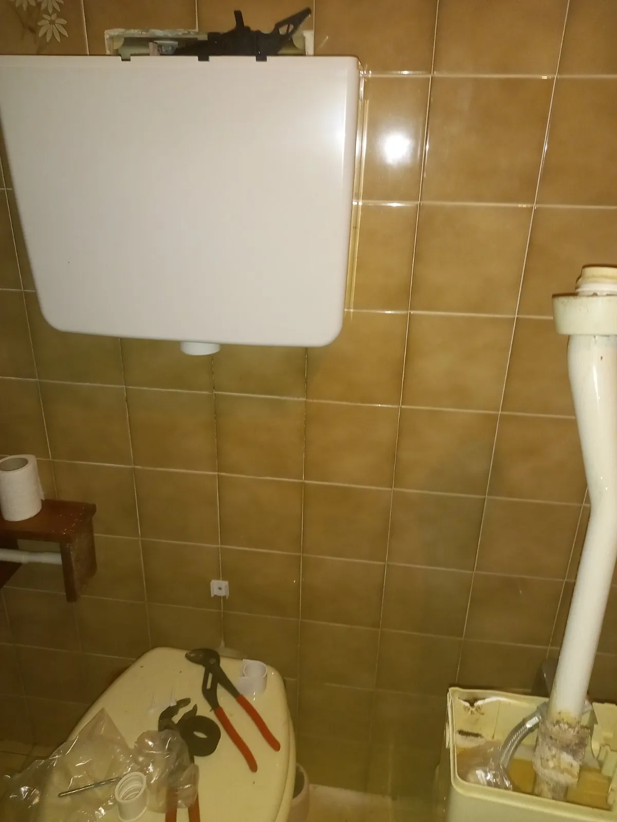 Cassetta nuova al muro con l'uscita ancora da collegare; a destra la vecchia cassetta con il tubo incrostato alla base