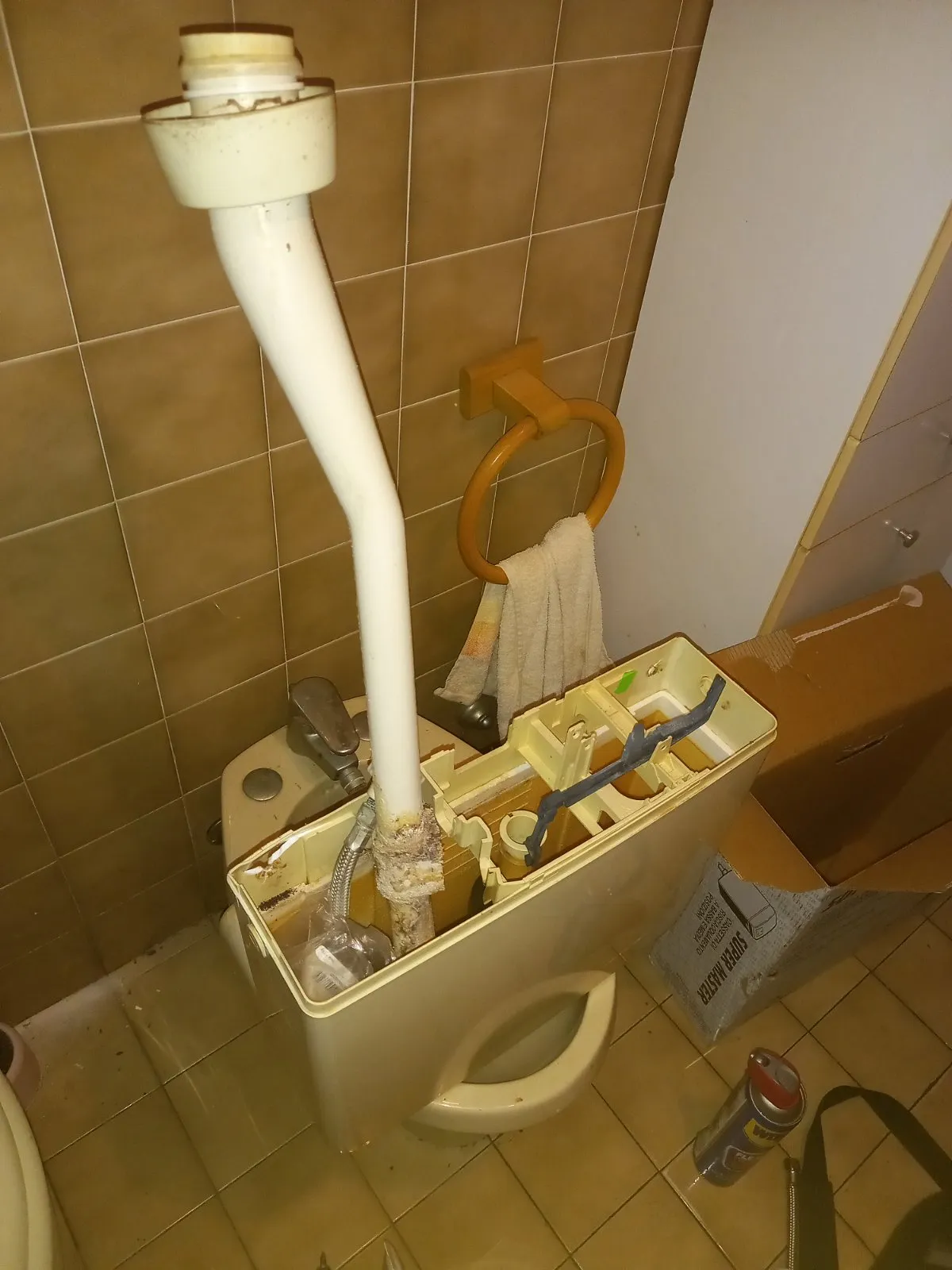 Vecchia cassetta del wc smontata e aperta: macchie scure all'interno e tubo di discesa coperto di incrostazioni in un tratto