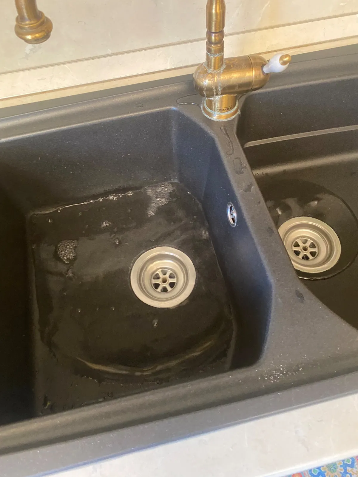 Lavello da cucina a due vasche con acqua ferma e schiuma nella vasca di sinistra che non scarica
