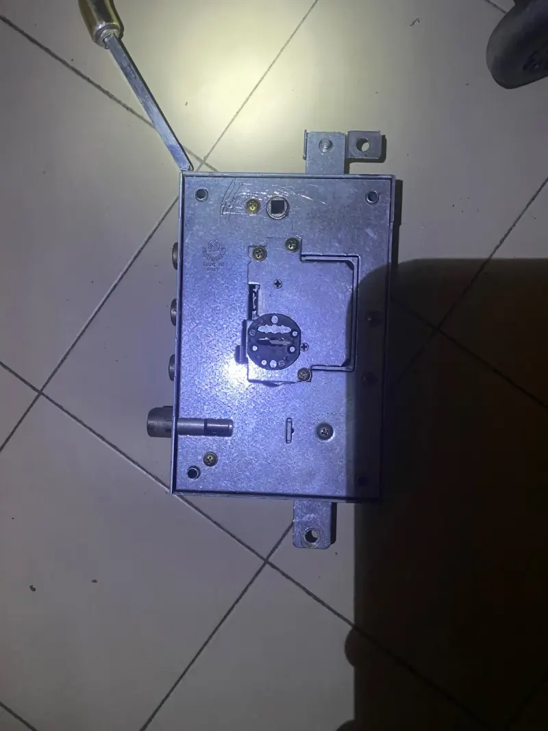 Serratura a doppia mappa di porta blindata fuori dalla porta, appoggiata a terra accanto a un cacciavite