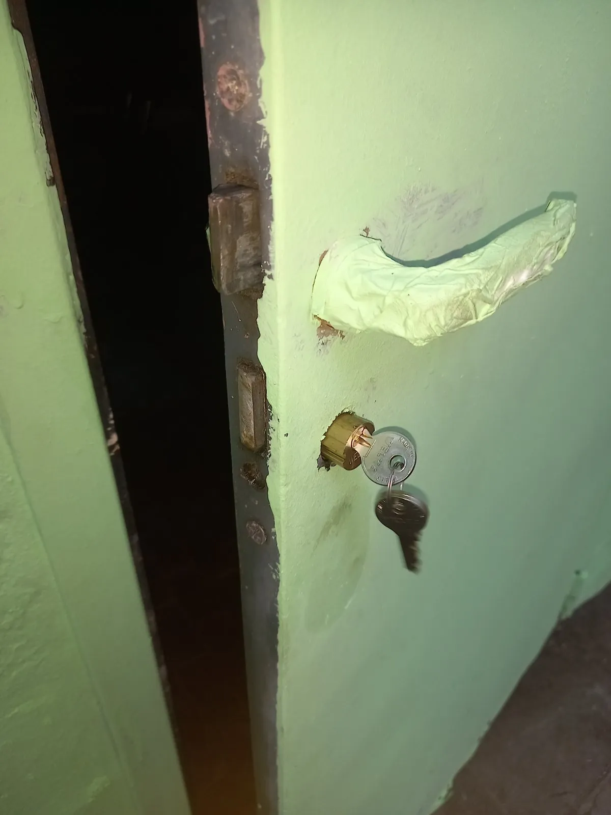 Porta del ripostiglio aperta con il cilindro nuovo in ottone montato e le chiavi inserite