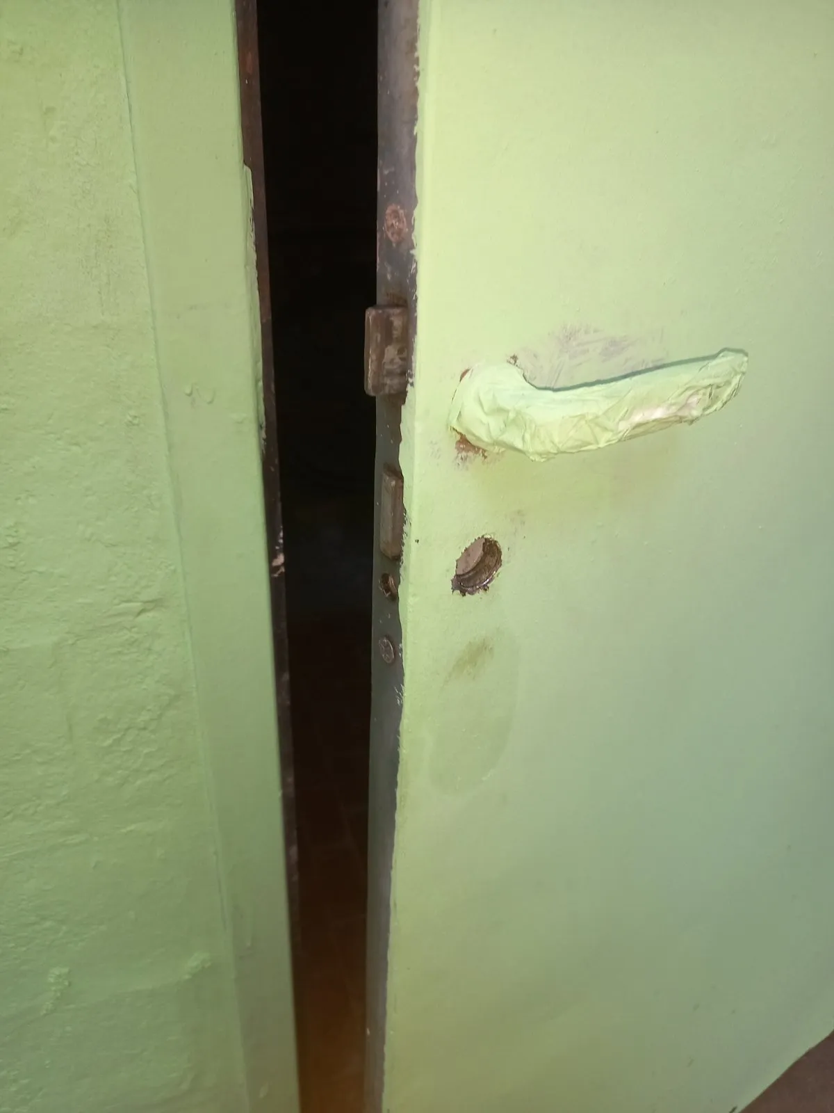 Porta del ripostiglio aperta dopo la perforazione, con il foro del cilindro vuoto sotto la maniglia