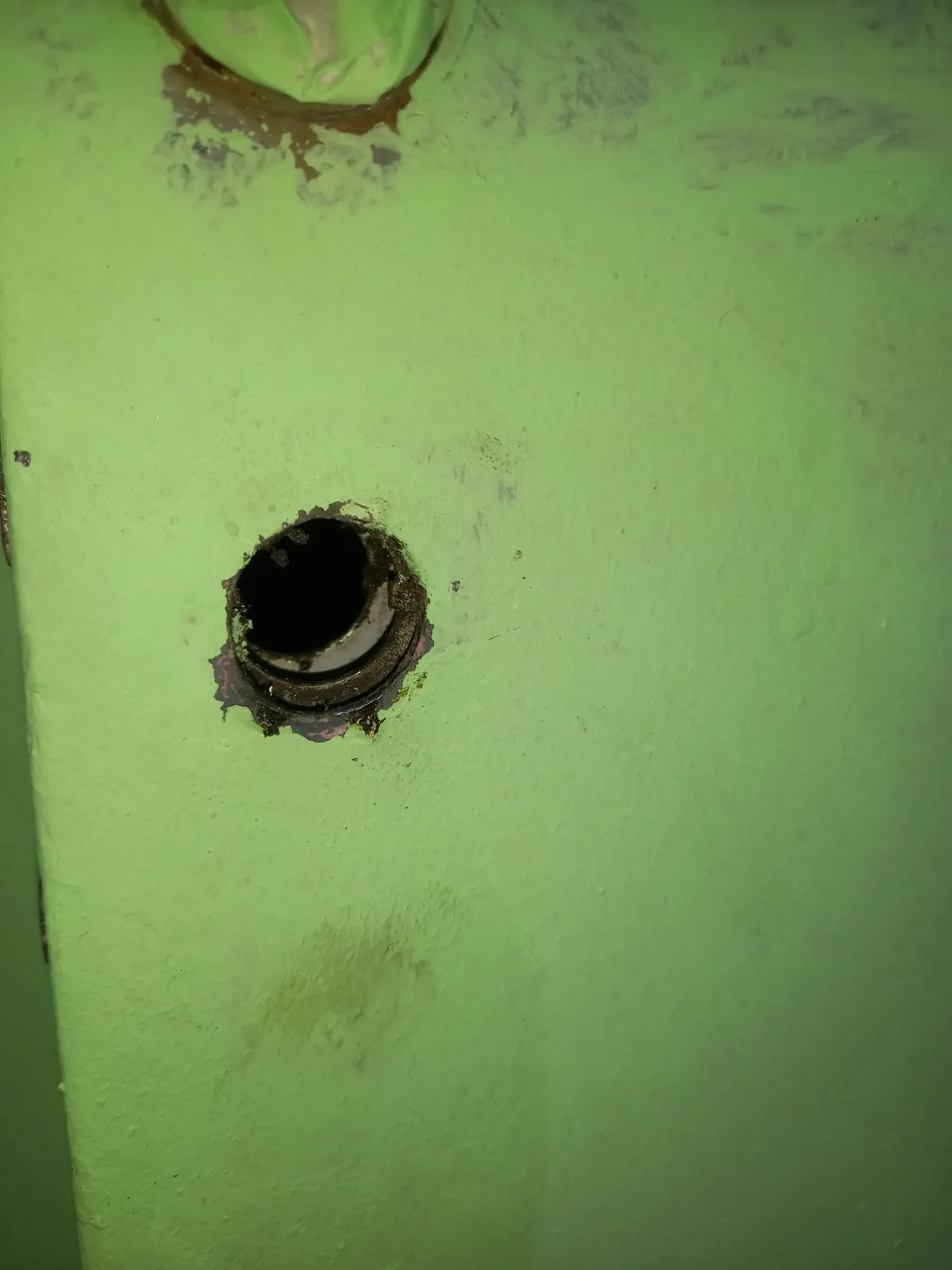 Primo piano della sede del cilindro svuotata, con ruggine e vernice scrostata sul bordo del foro