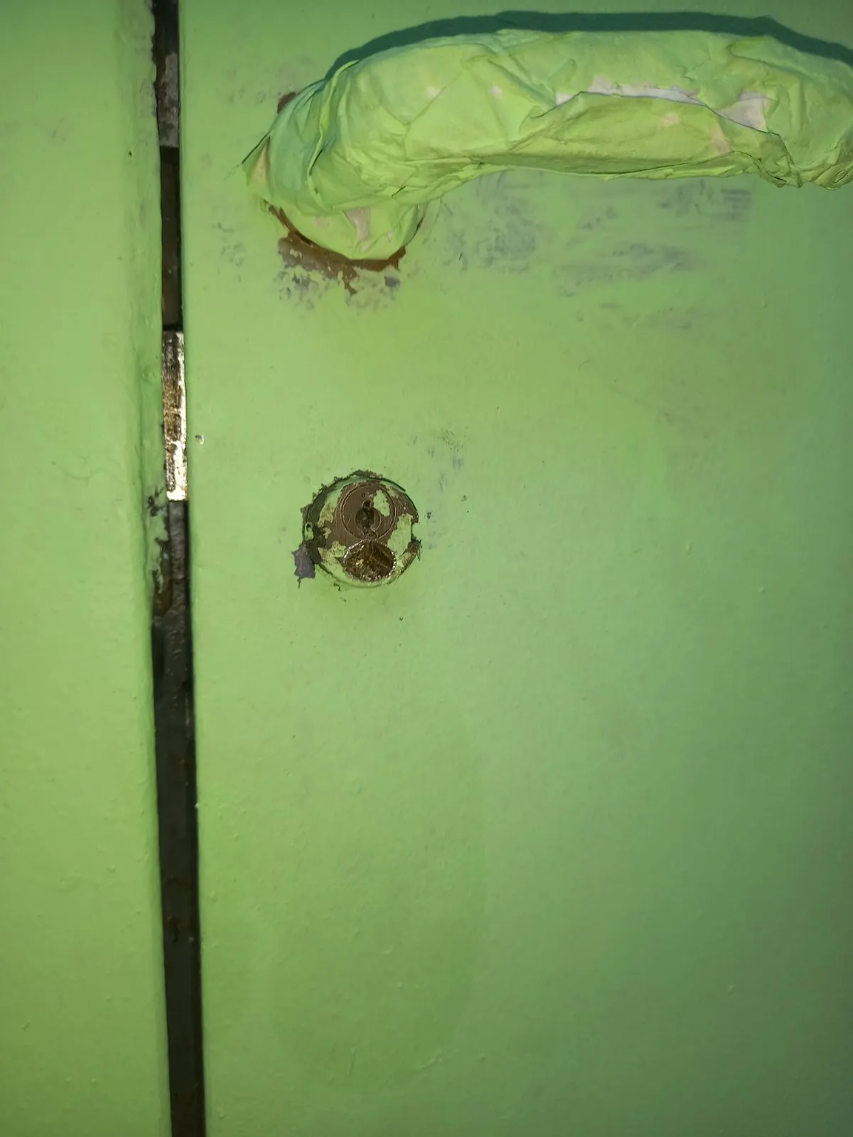Vecchio cilindro bloccato con la faccia coperta di vernice verde, sotto la maniglia avvolta nel nastro