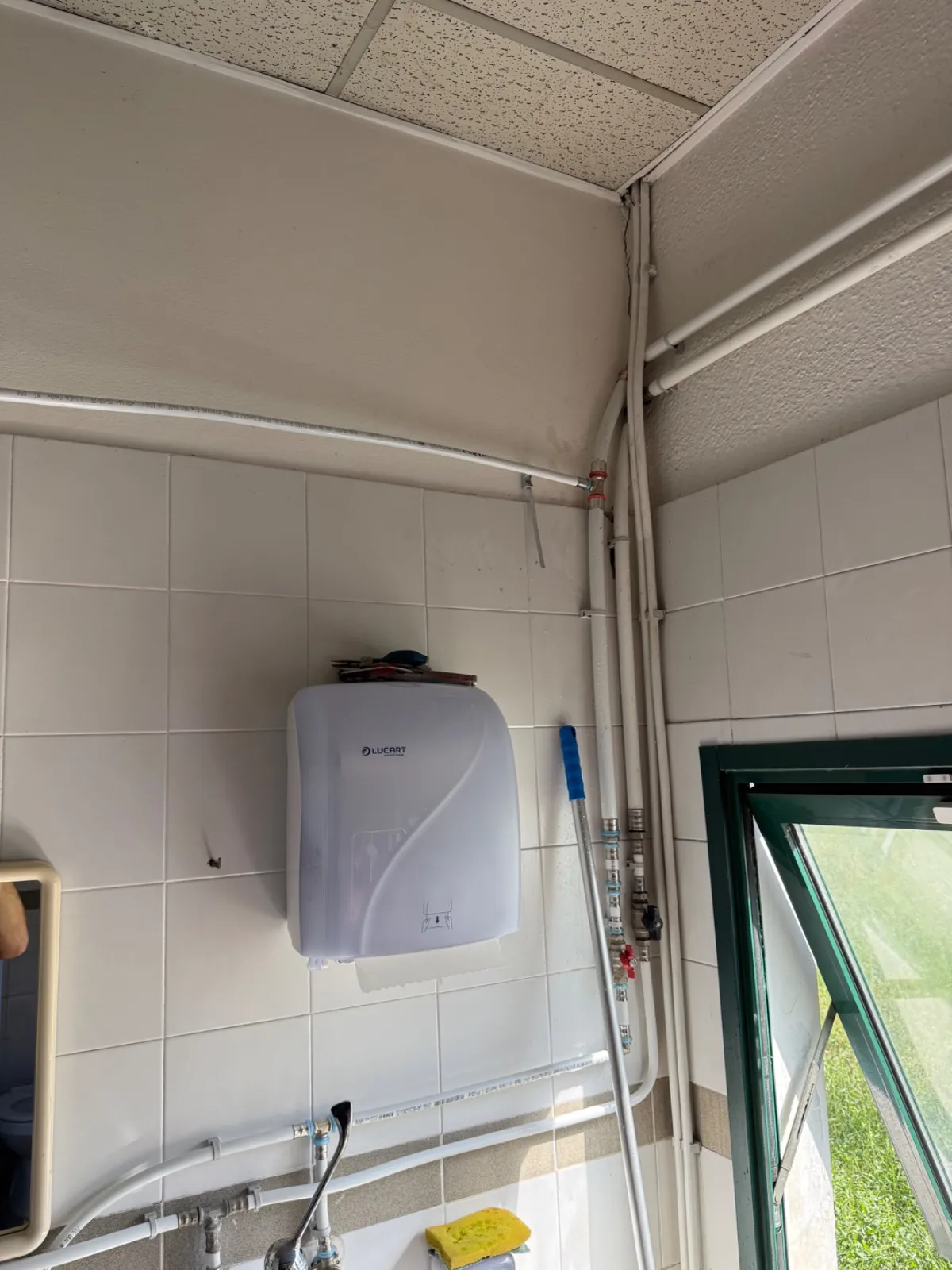 Parete piastrellata del bagno: il nuovo tubo multistrato corre in alto e si collega ai tubi verticali nell'angolo